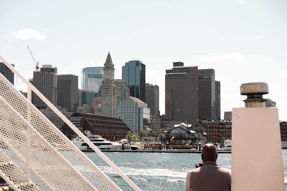 um homem sentado em um barco olhando para uma cidade