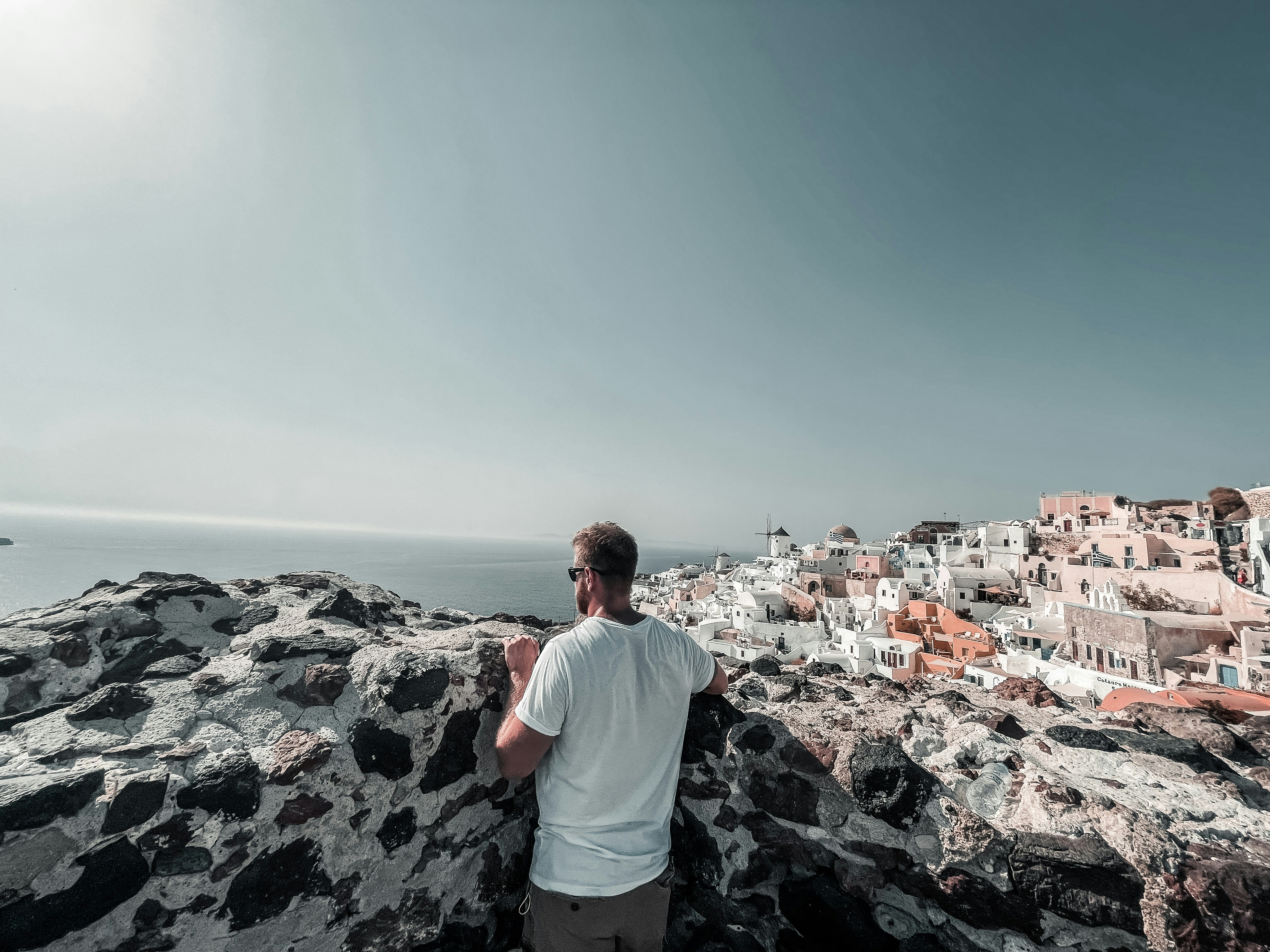 海の隣の岩だらけの崖の上に立つ男