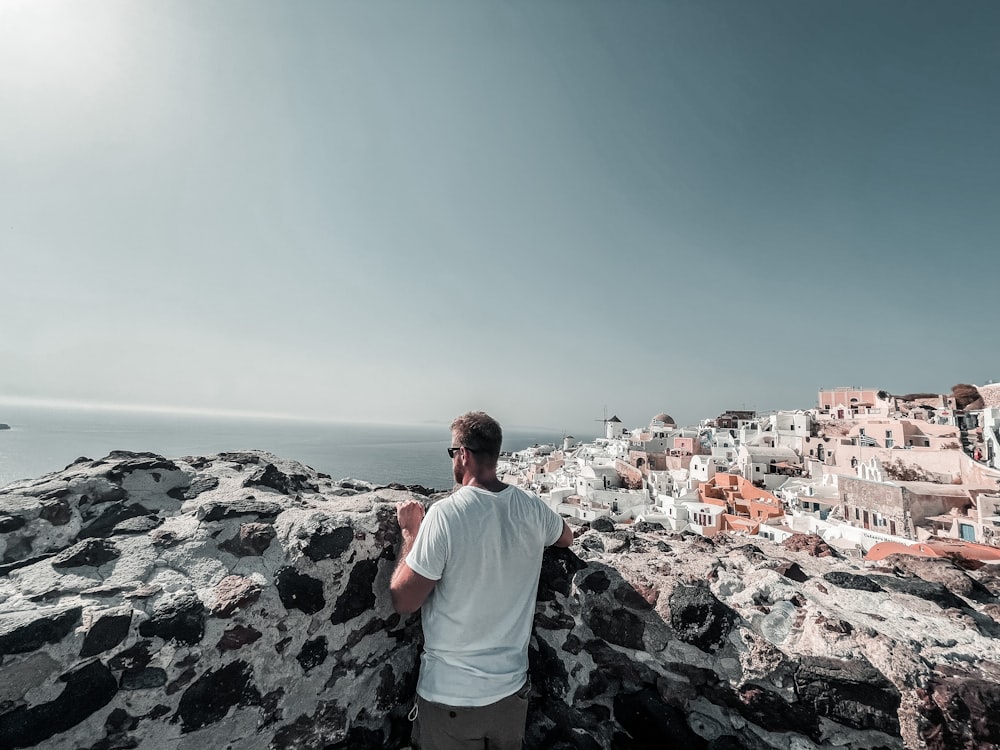 a man standing on top of a rocky cliff next to the ocean
