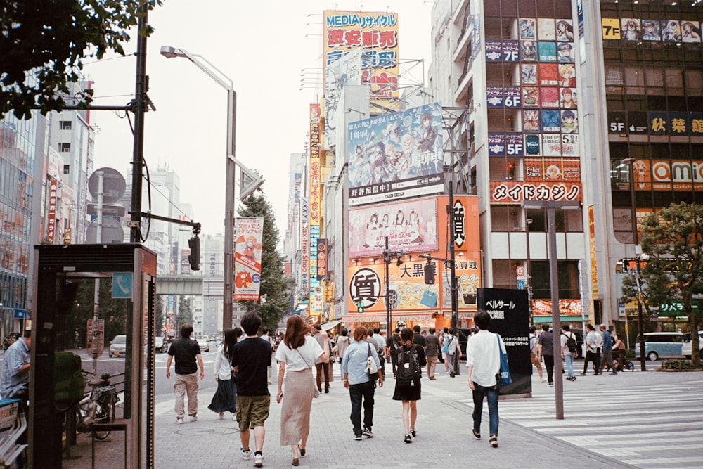 a group of people walking down a street next to tall buildings