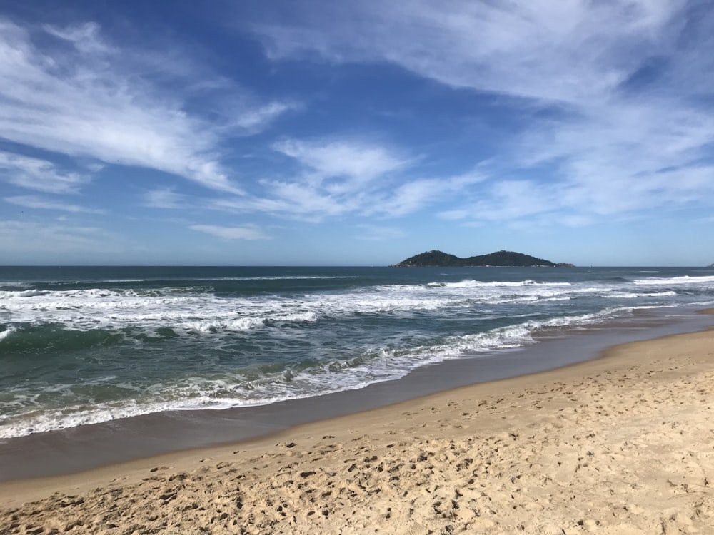 a sandy beach with waves coming in to shore