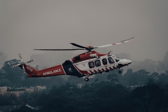 a red and white helicopter flying over a city