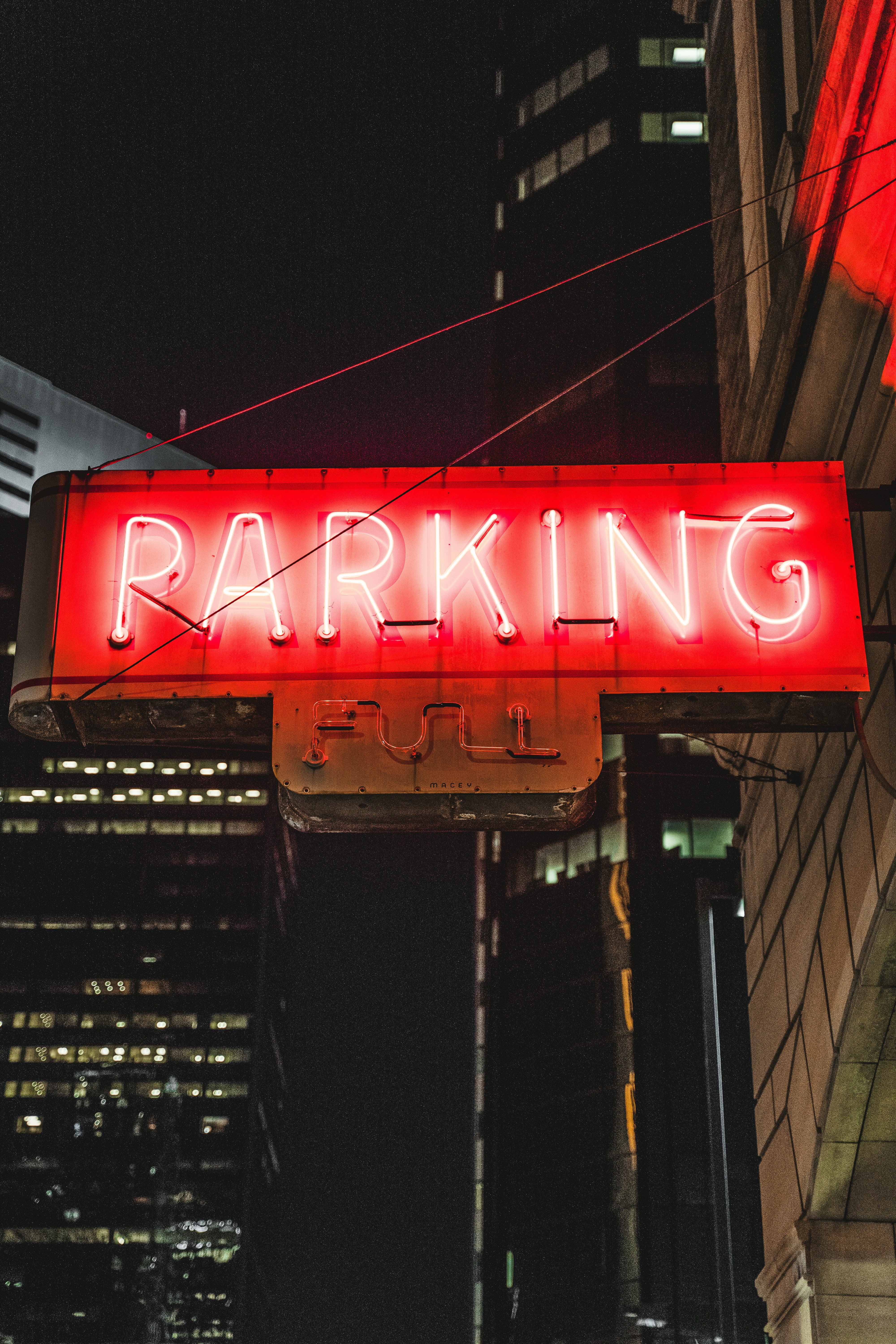a neon sign that says parking on a city street