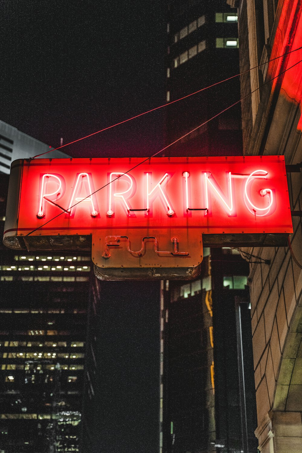 a neon sign that says parking on a city street