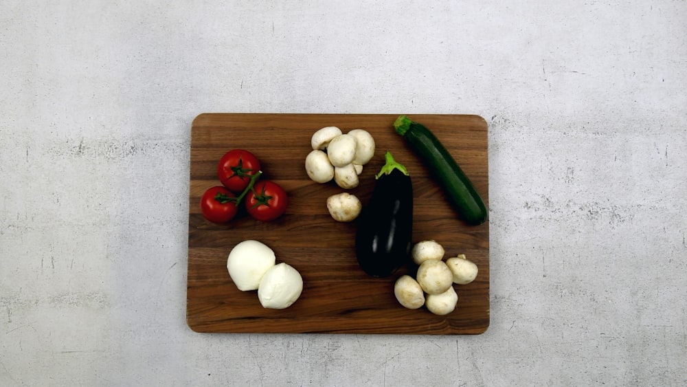 a cutting board topped with vegetables on top of a table
