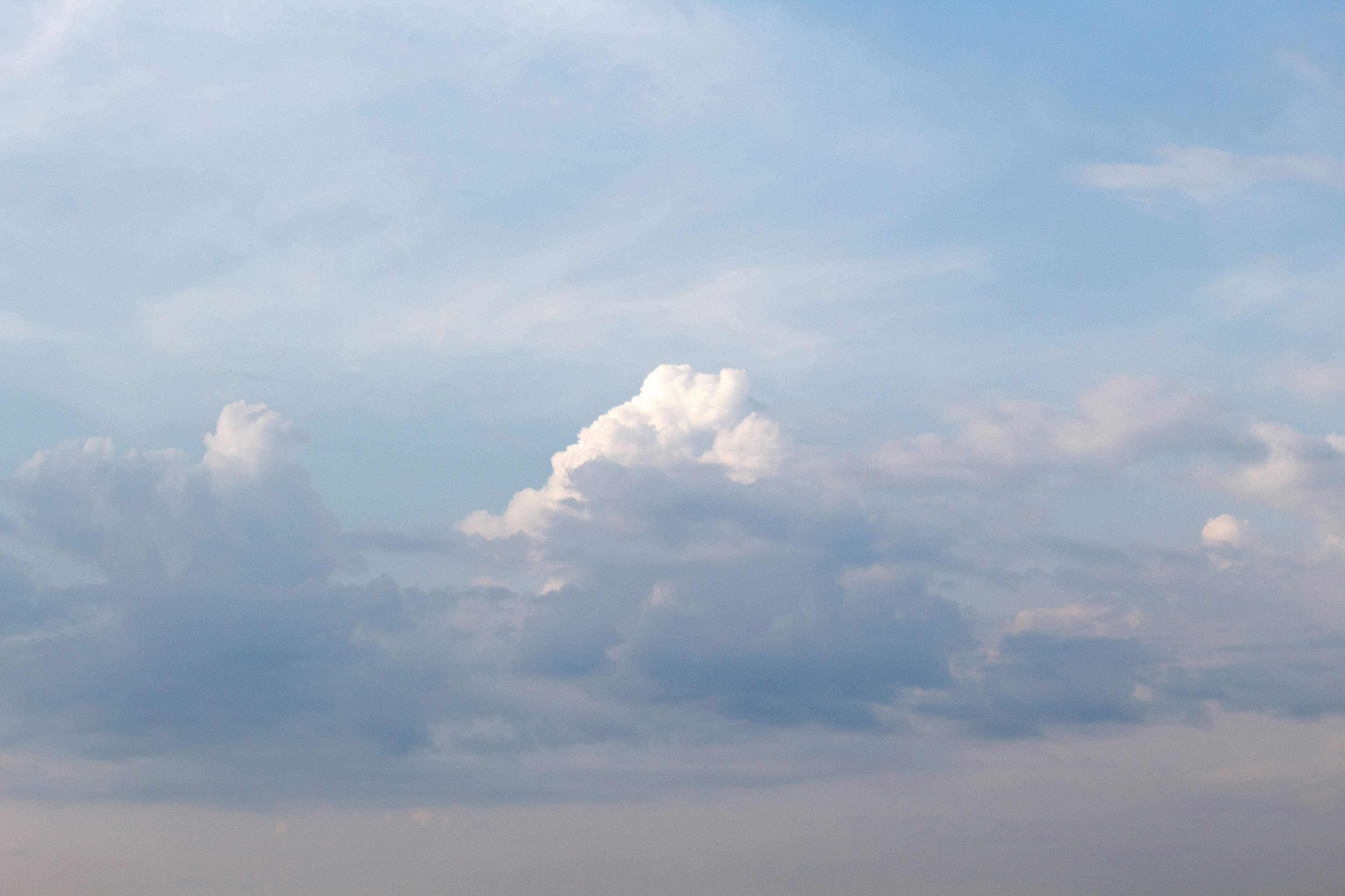 a plane flying through a cloudy blue sky
