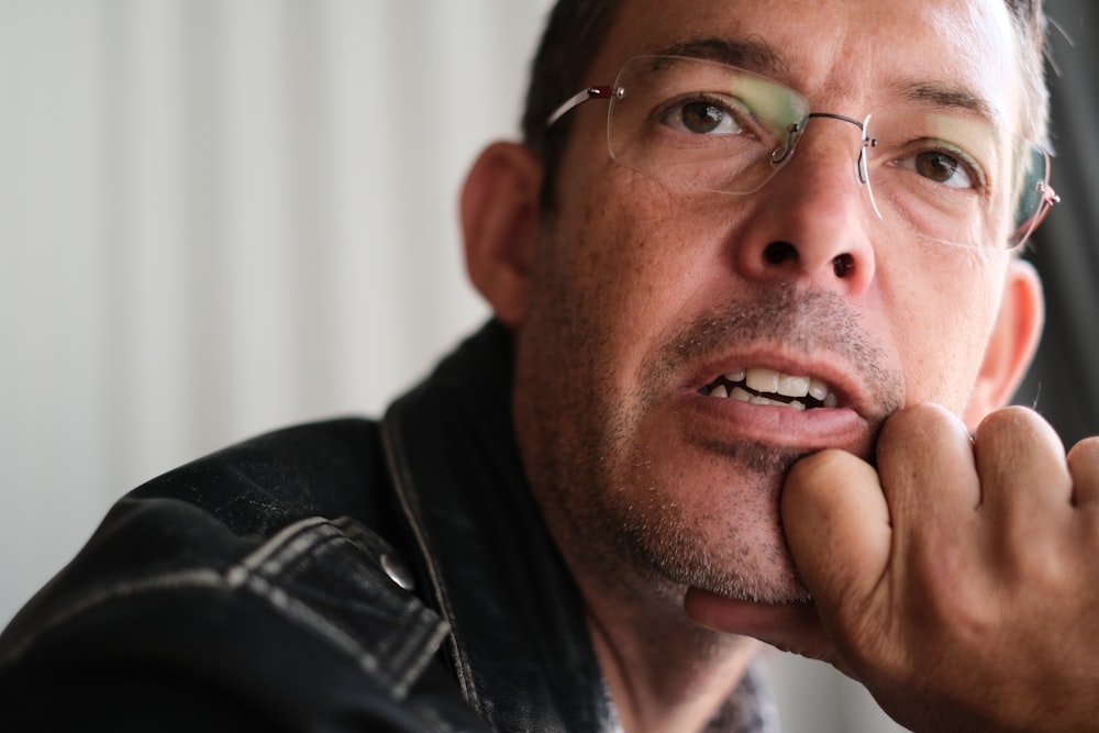 a man wearing glasses and a leather jacket