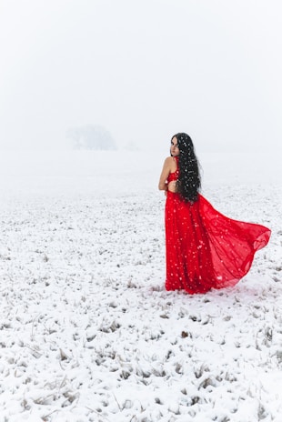 A model wearing a full-length dress in deep navy against a snowy backdrop.