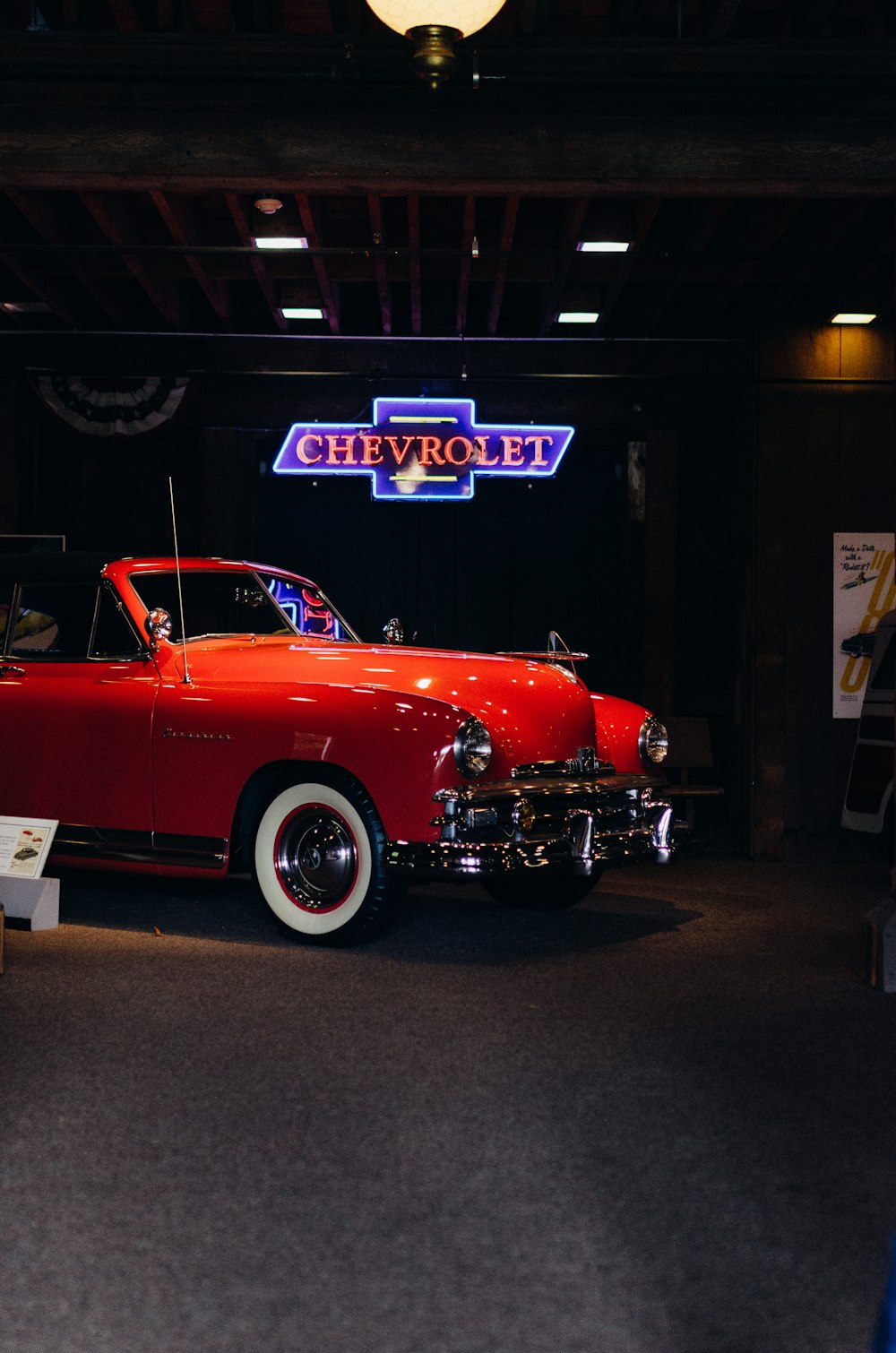 a red car parked in a garage next to a neon sign