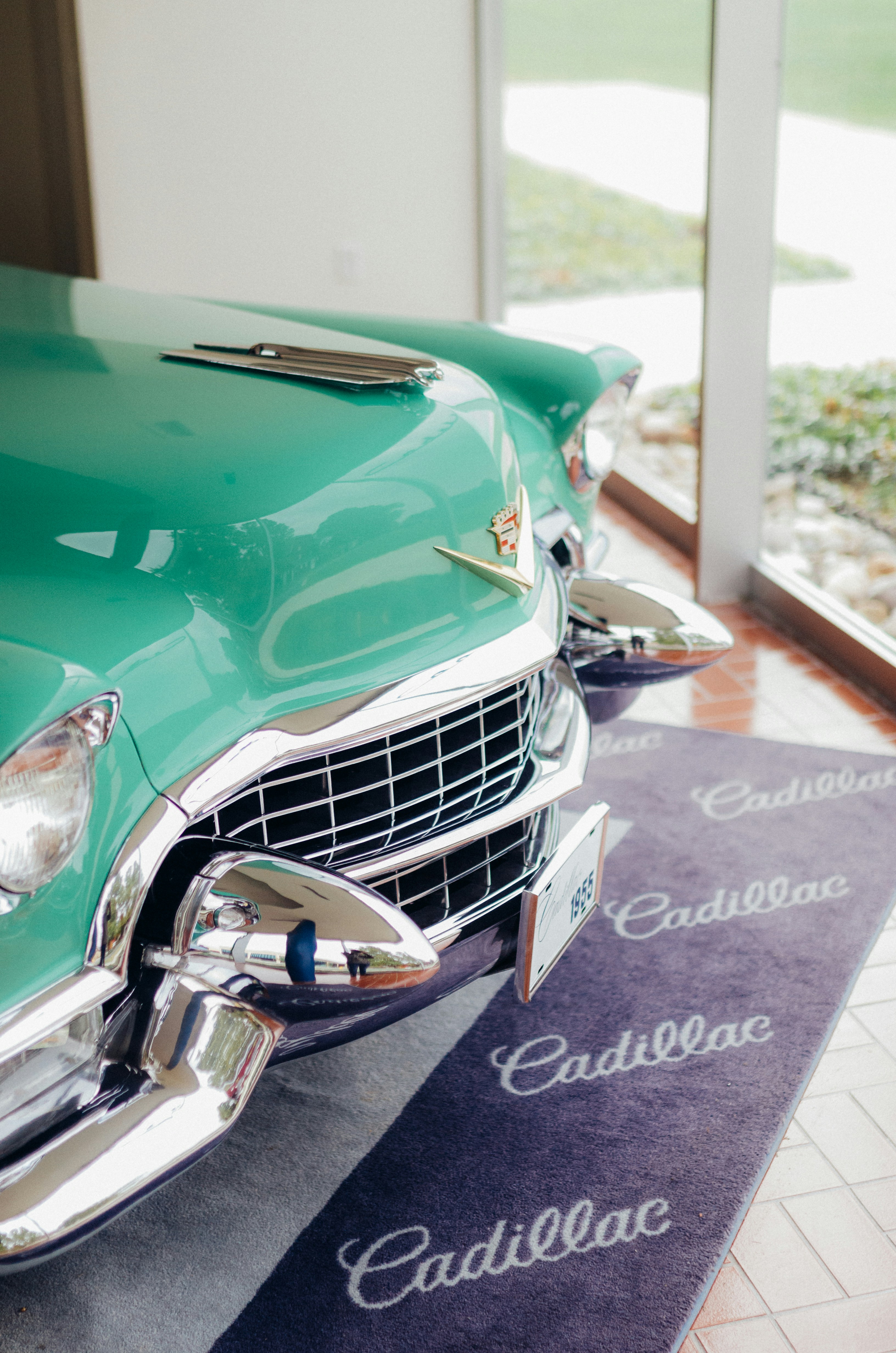 a green classic car parked in a garage