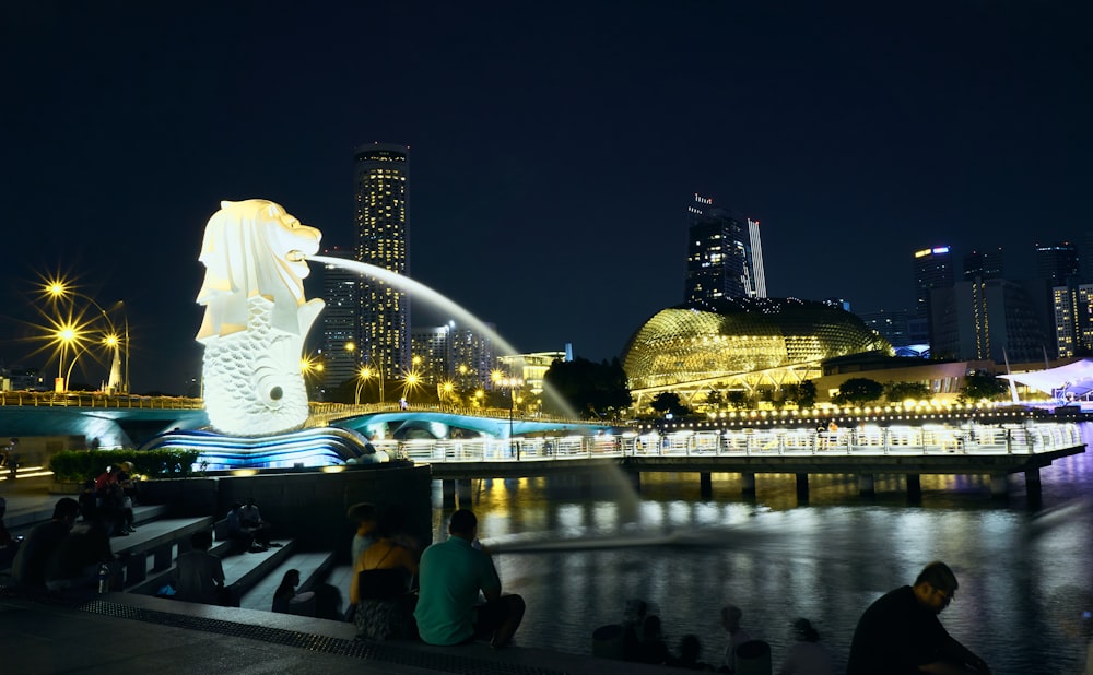 people sitting on the edge of a river at night