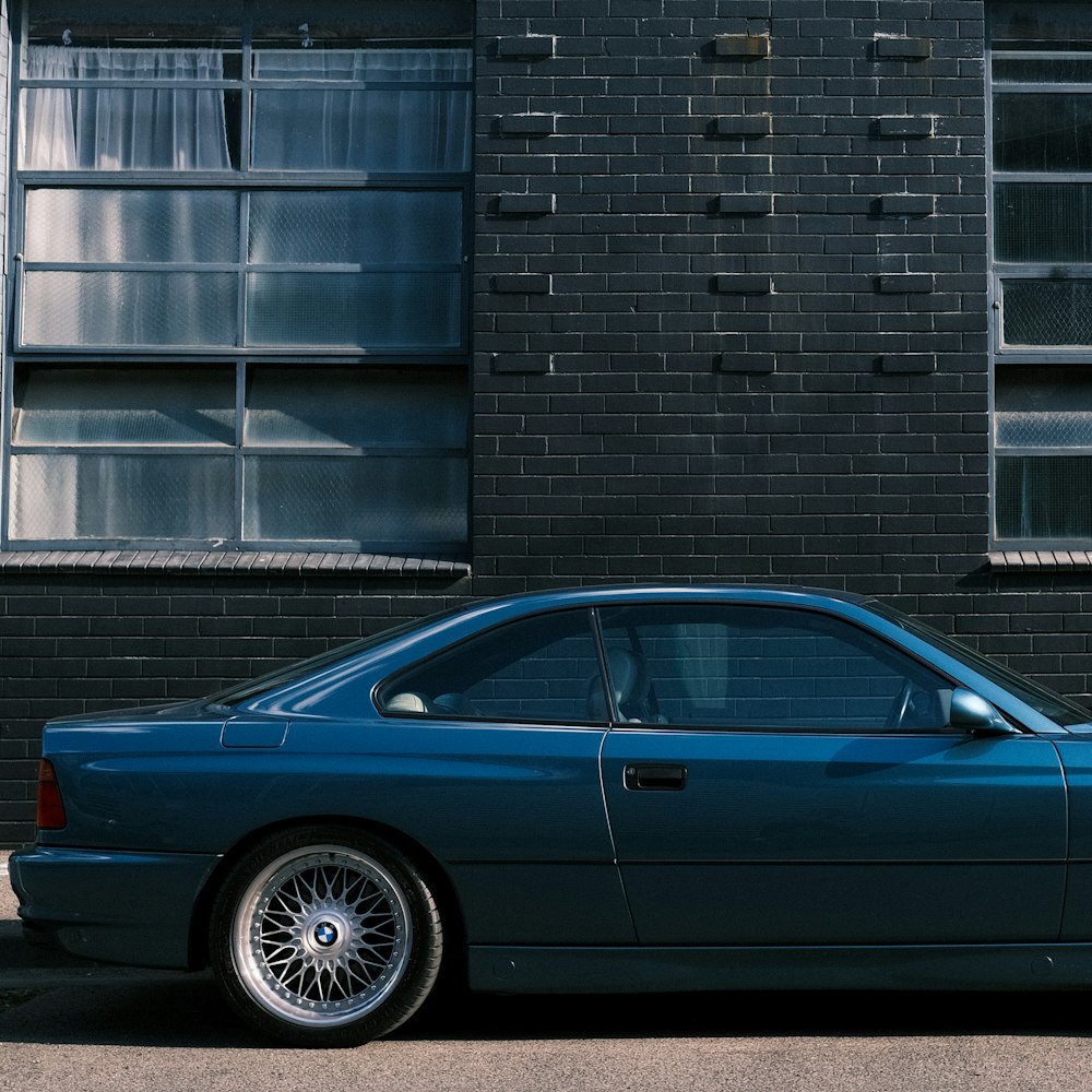 a blue car parked in front of a brick building