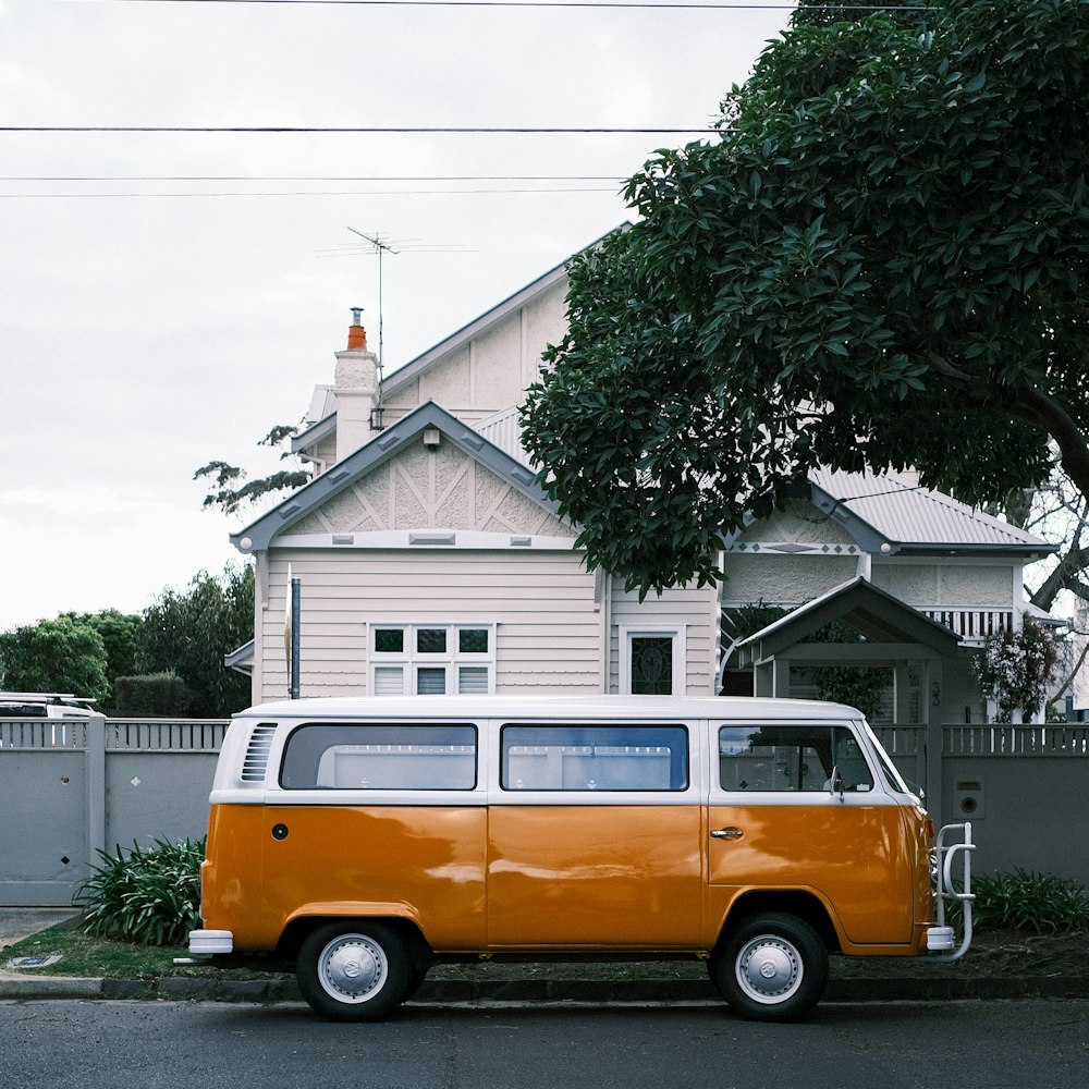 an orange and white van parked in front of a house