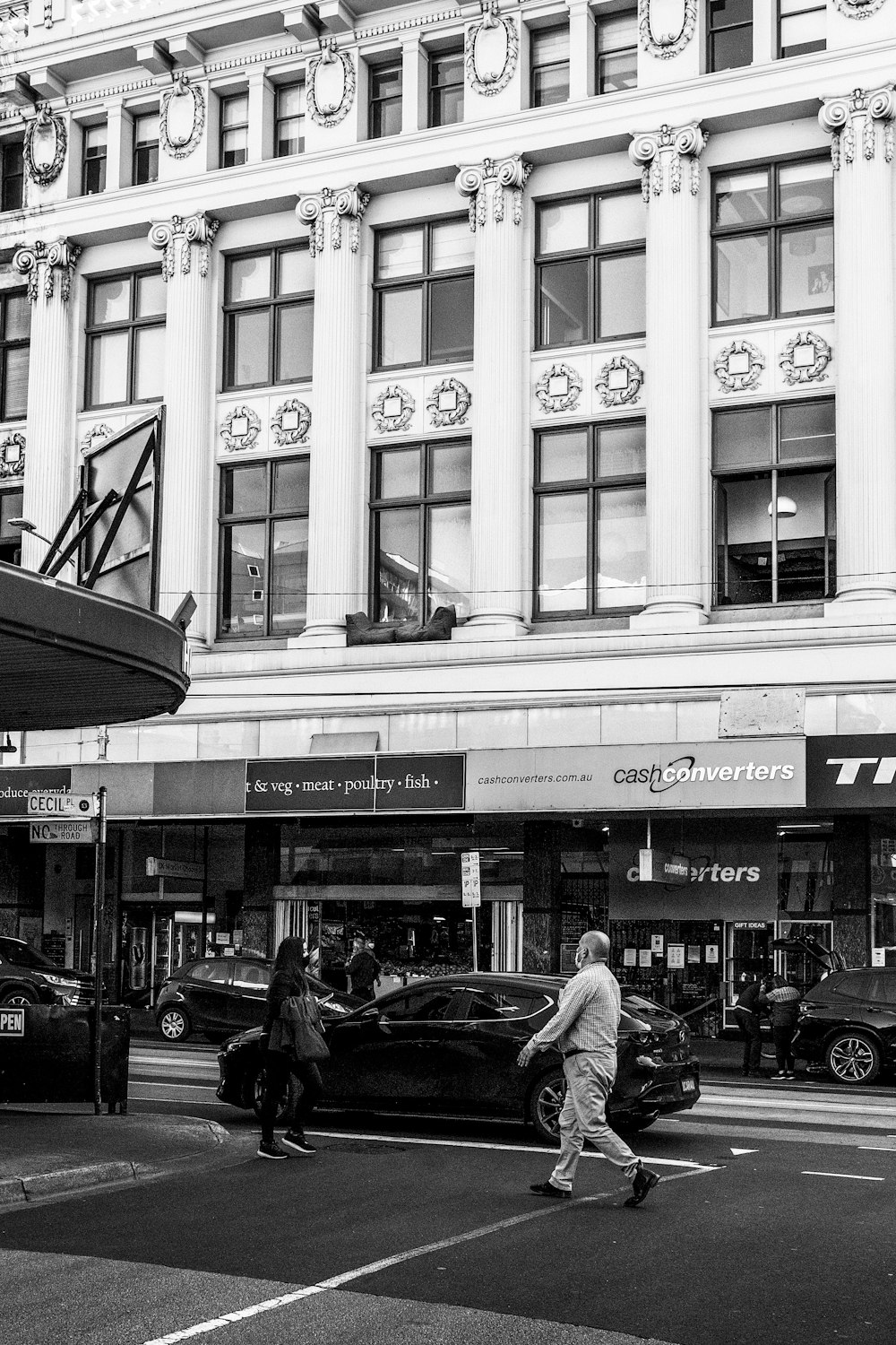 a black and white photo of people crossing the street