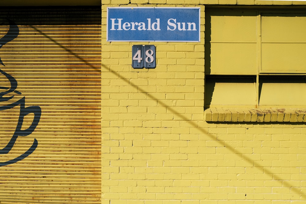 a yellow brick building with a blue sign on it