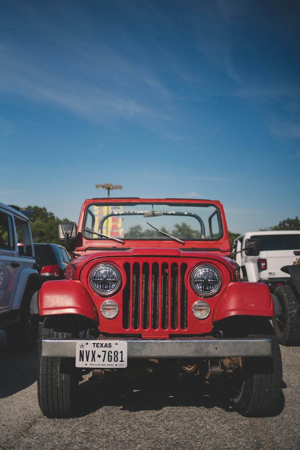 a red jeep is parked in a parking lot