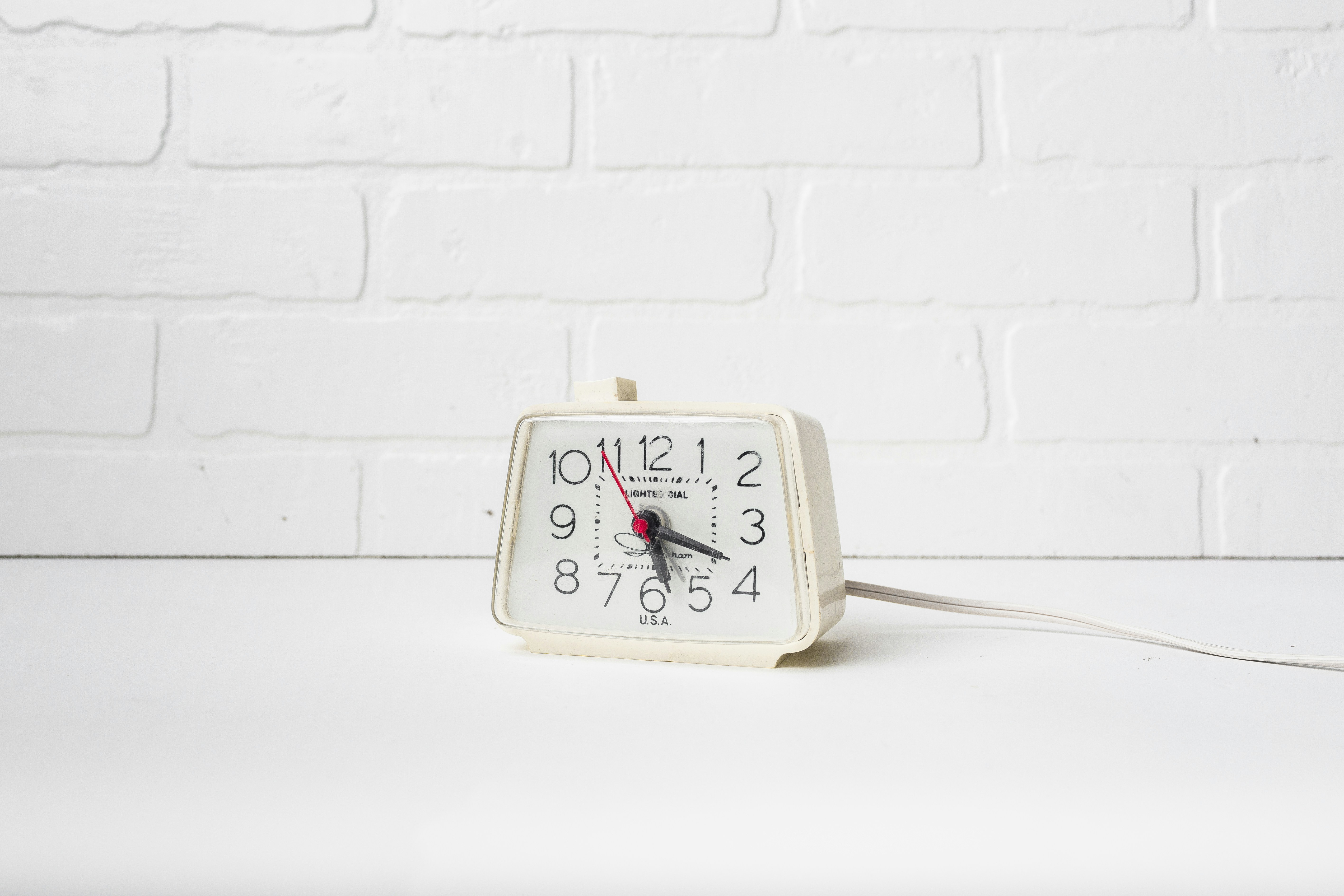 Eine weiße Uhr sitzt auf einem weißen Tisch