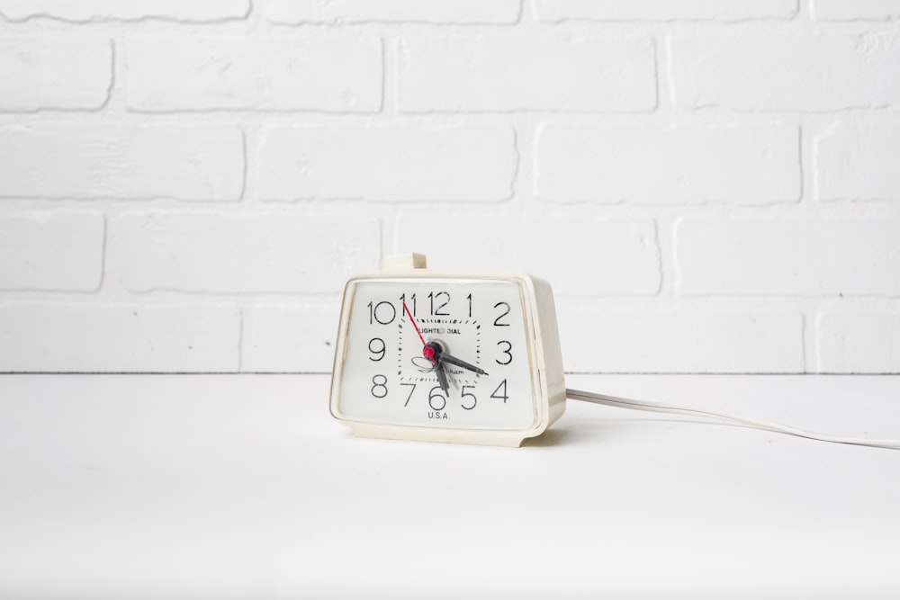 a white clock sitting on top of a white table