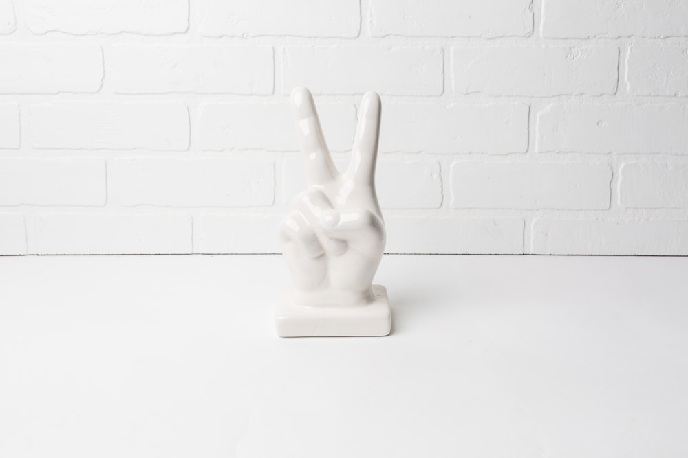 a white statue of a peace sign on a white table