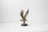 Close-up of a detailed bronze eagle sculpture perched on a natural wood base.