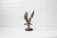 Close-up of a detailed bronze eagle sculpture perched on a natural wood base.