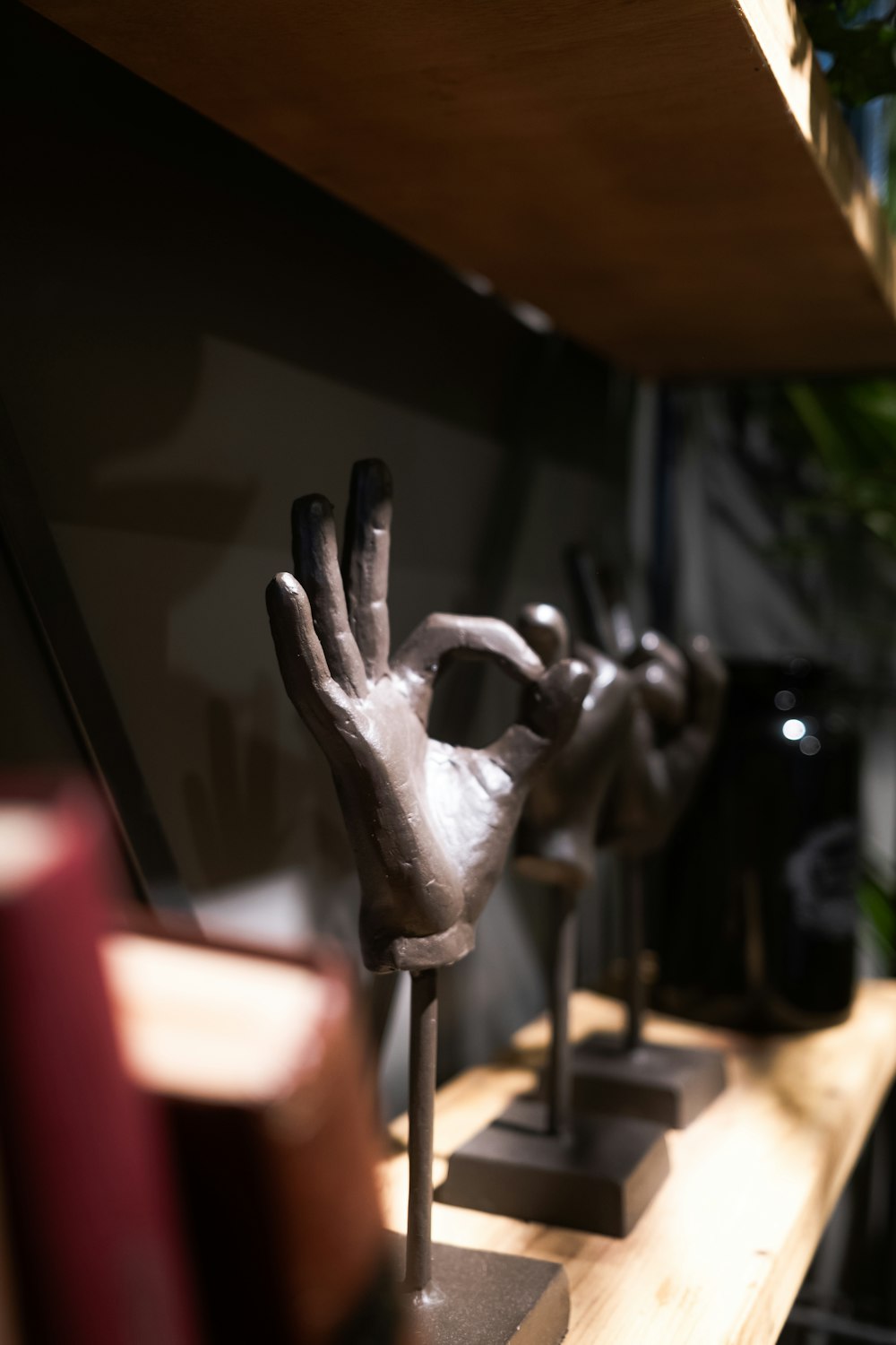 a row of hand sculptures sitting on top of a wooden shelf