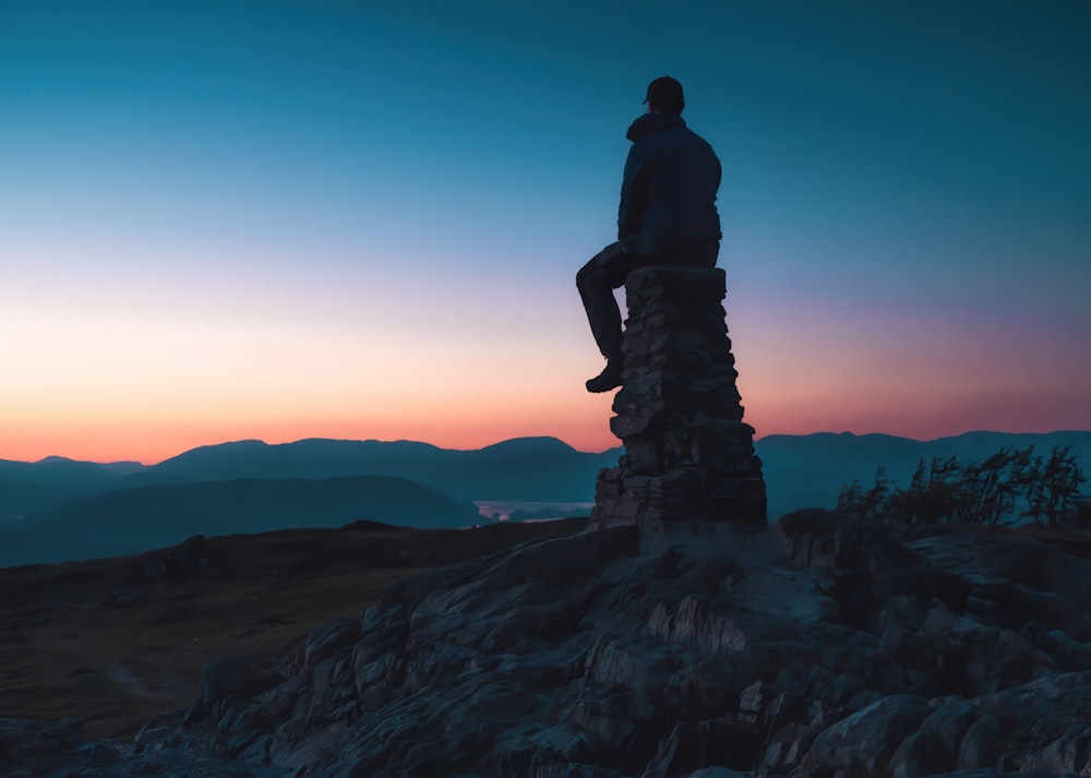 a man sitting on top of a rock formation