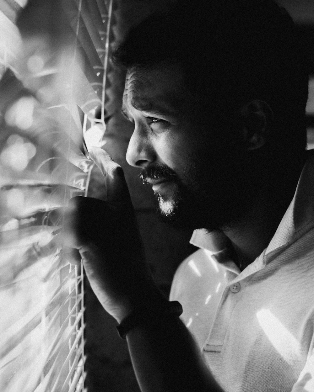 a black and white photo of a man looking out a window