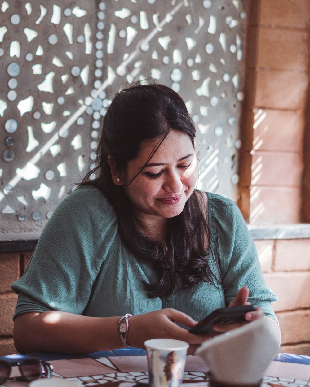 a woman sitting at a table looking at her cell phone