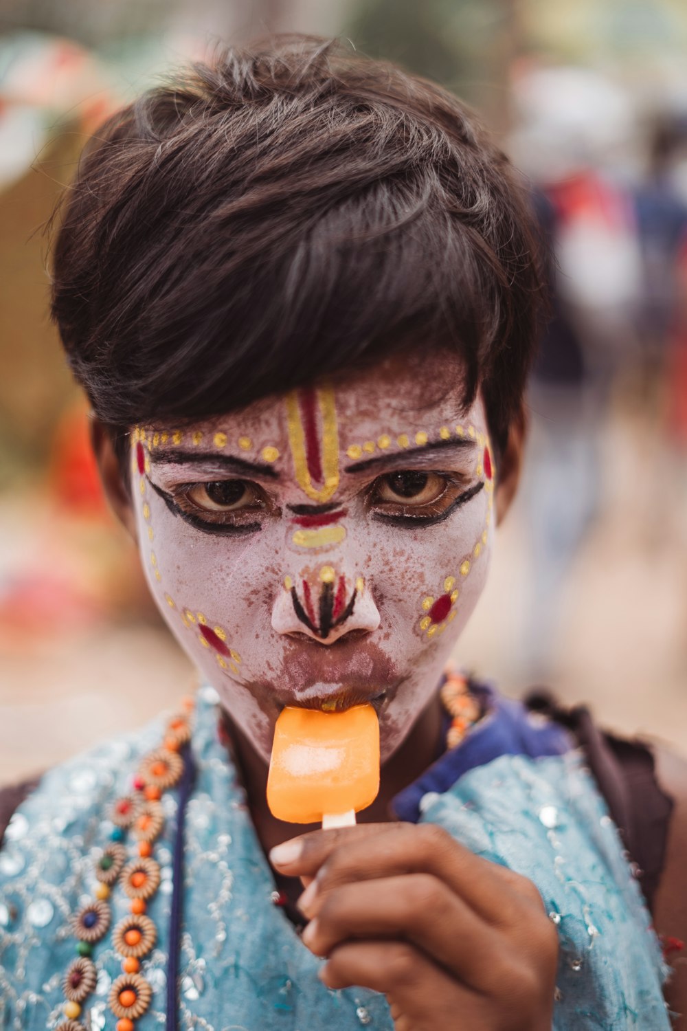 a person with face paint holding a lollipop