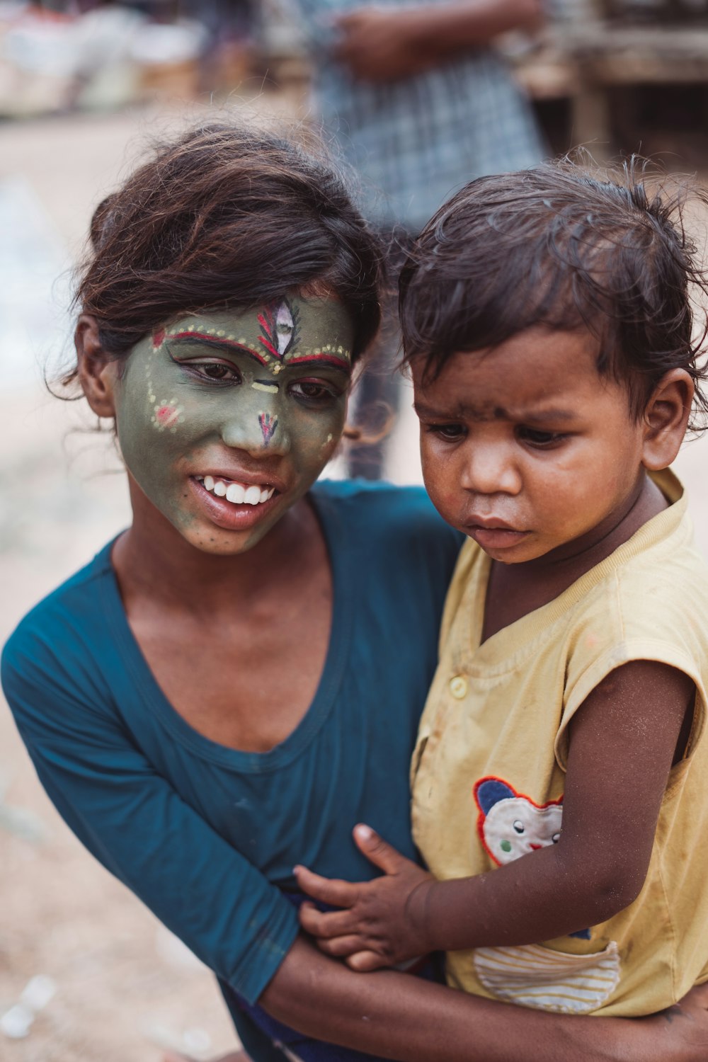 a woman holding a child with a painted face