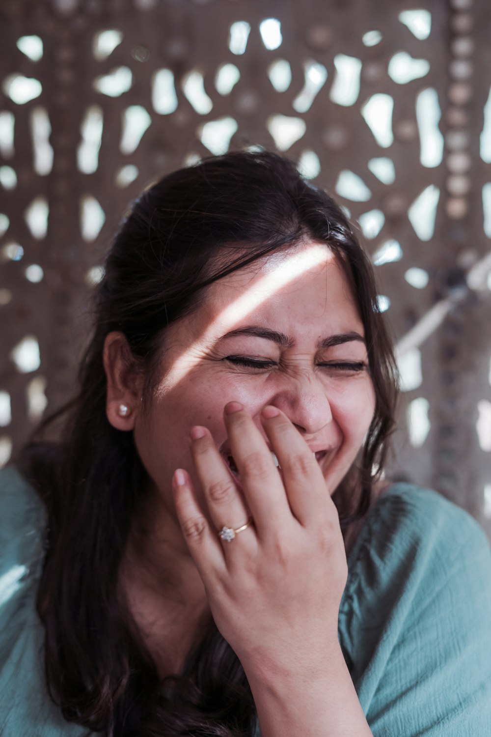 a woman laughing while holding her hand to her face