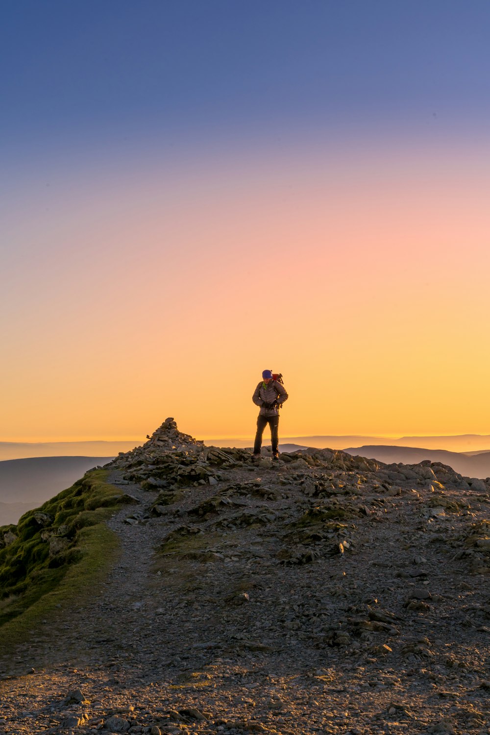 a person standing on top of a hill at sunset