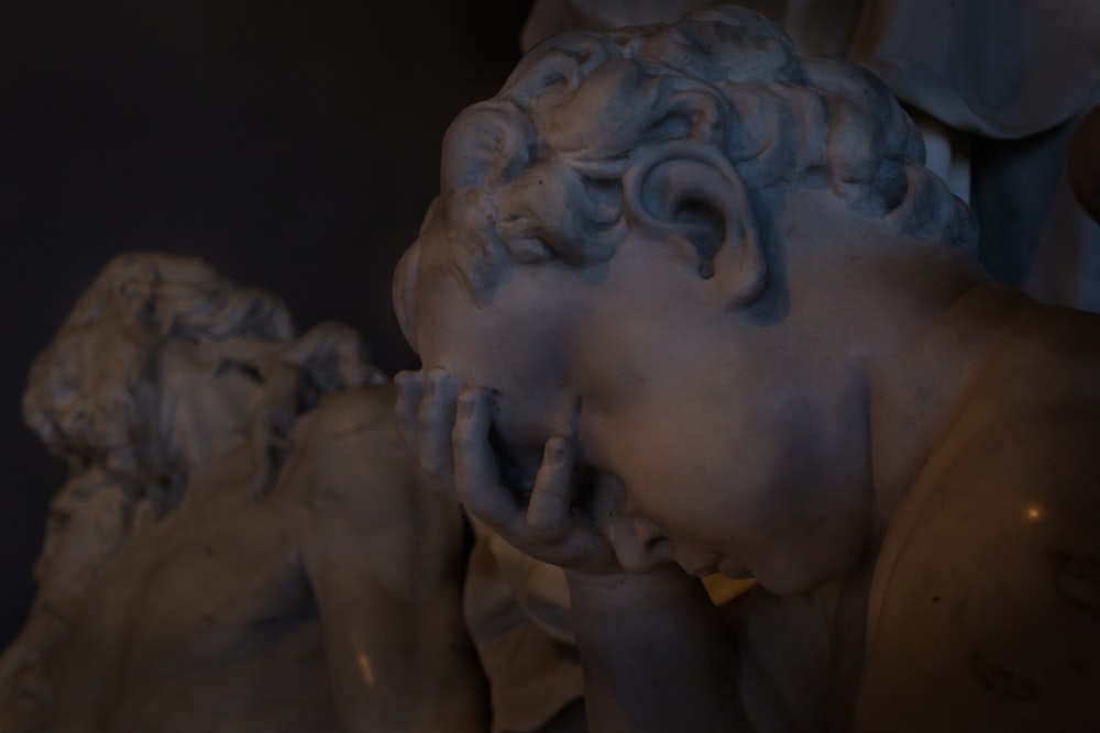 a close up of a statue of a man with his hands on his face