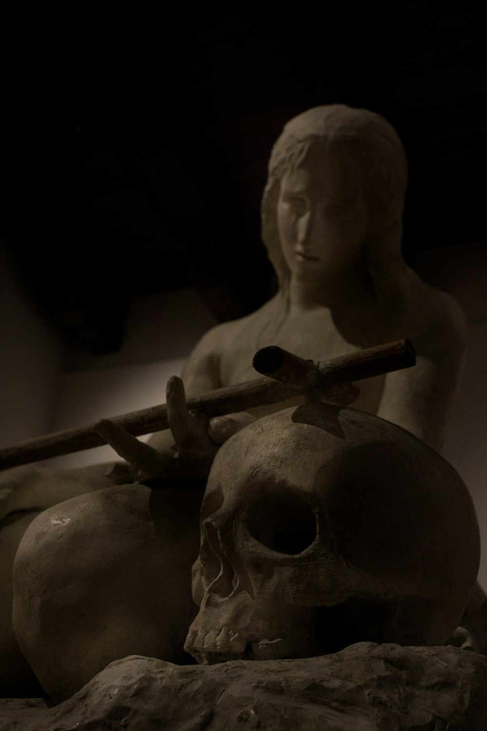 a statue of a woman holding a stick and a skull
