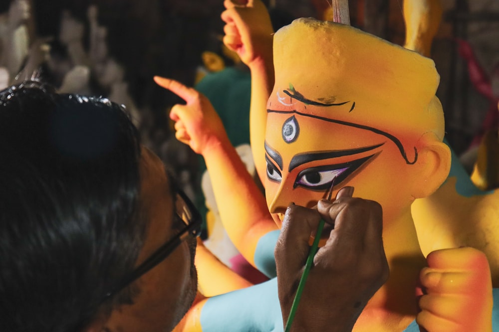 a woman is painting a mask on a man's face