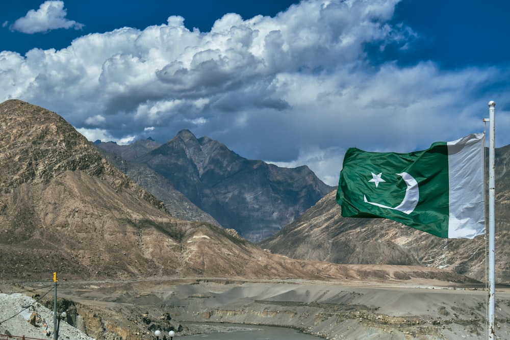 a pakistan flag flying in front of a mountain range