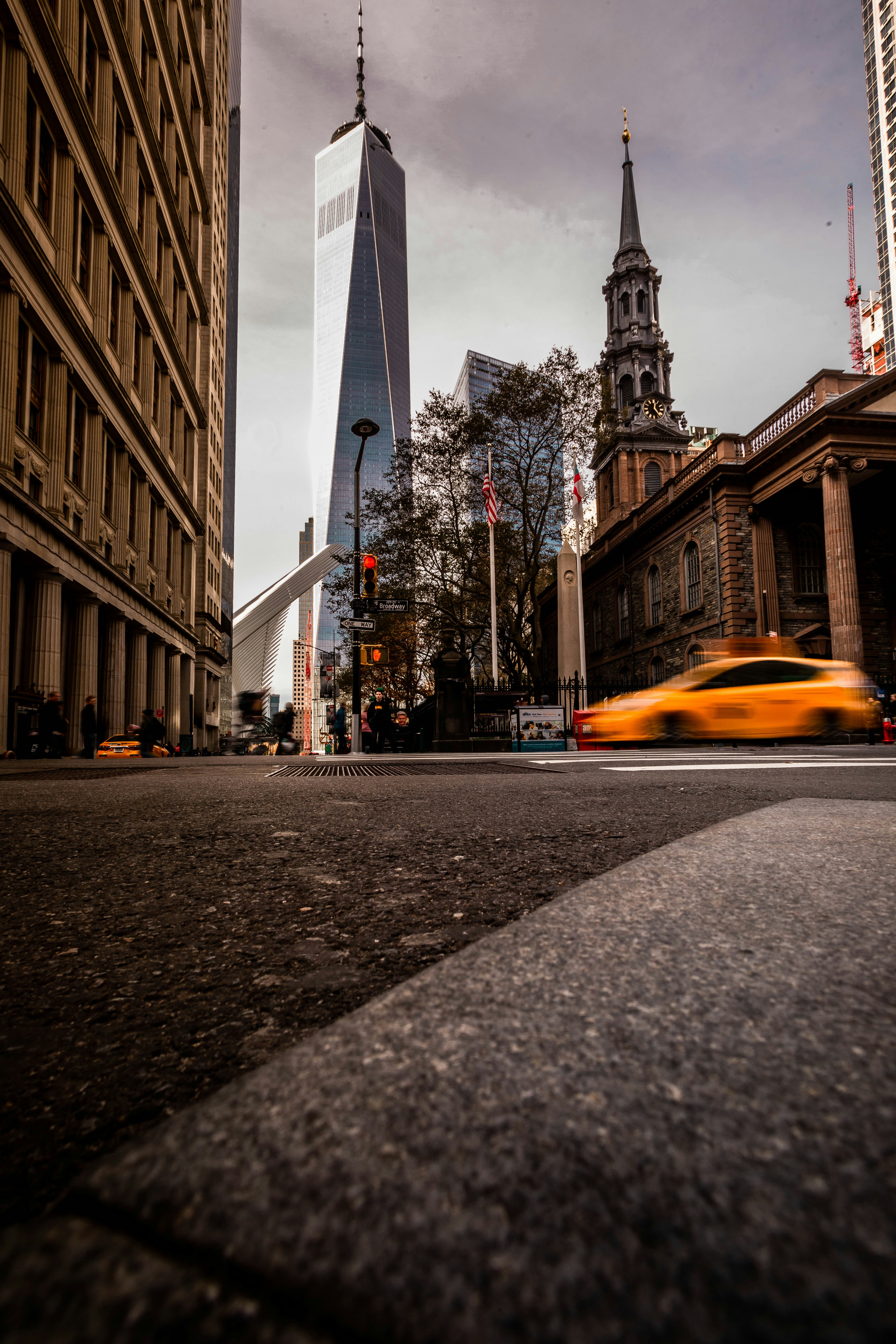 Ein gelbes Auto fährt eine Straße neben hohen Gebäuden entlang