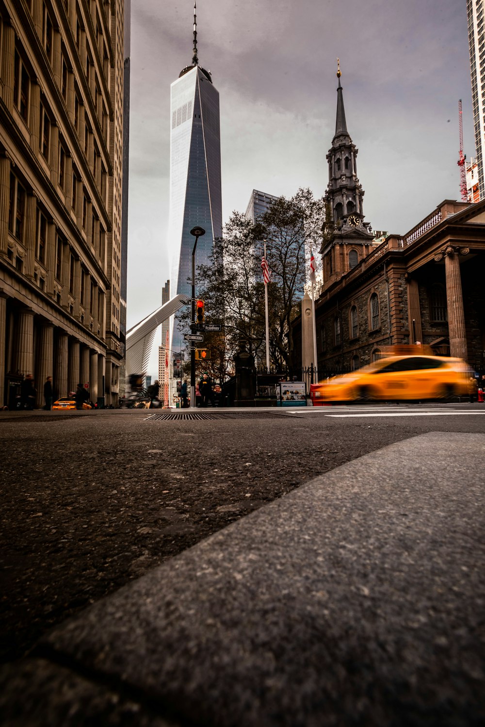 a yellow car driving down a street next to tall buildings