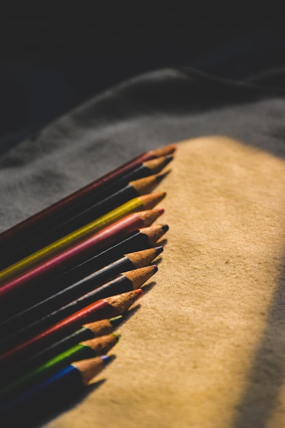 A colorful assortment of pencils neatly arranged on a wooden desk with a soft natural light.