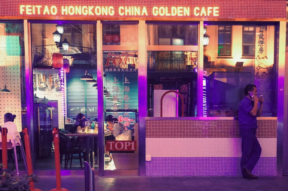 a man standing outside of a restaurant at night