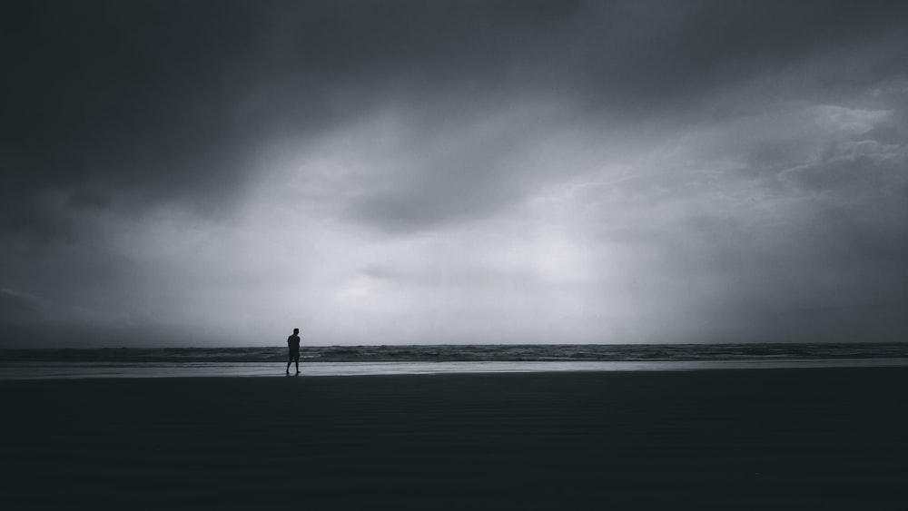 a person standing on a beach under a cloudy sky