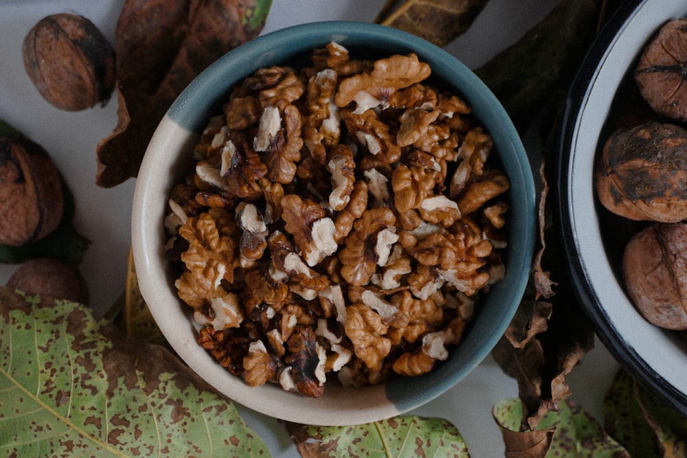 a bowl filled with nuts next to a bowl of walnuts