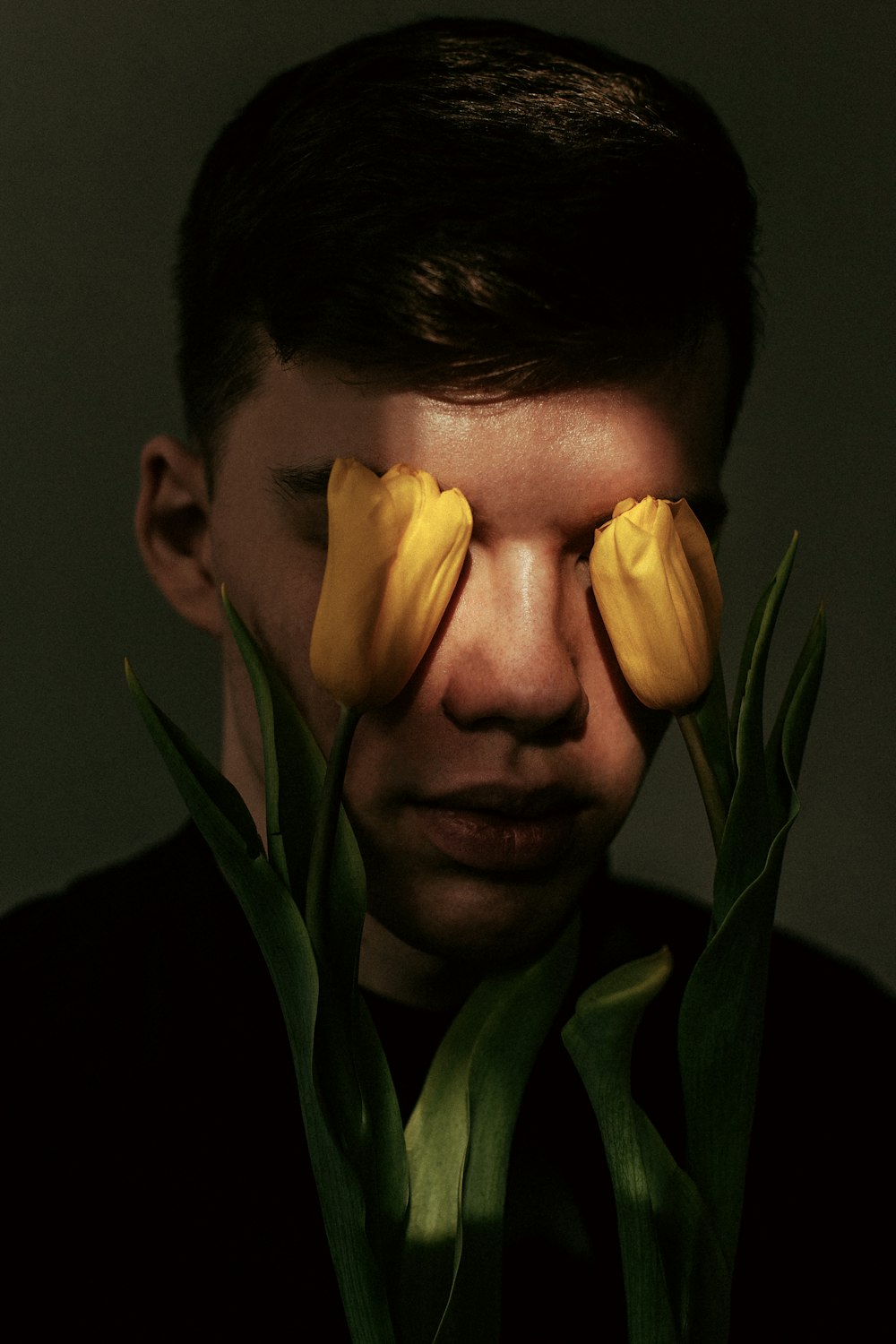a man with two yellow flowers covering his eyes