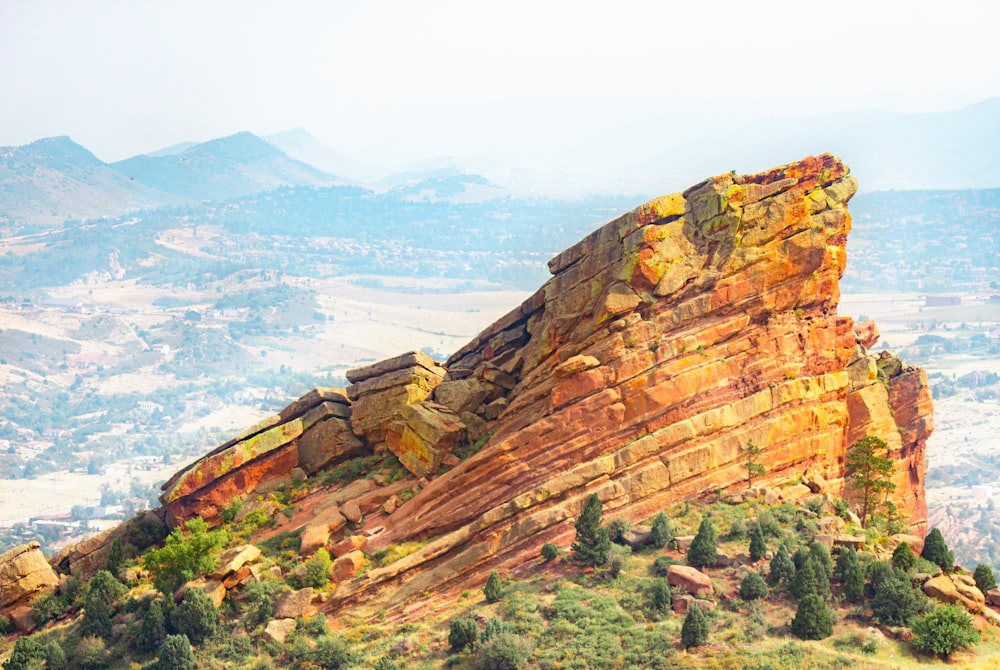 a rocky outcropping with trees and mountains in the background