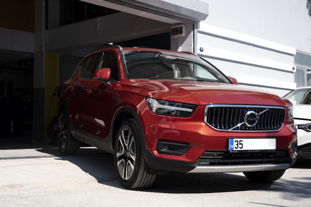 a red volvo car parked in front of a building