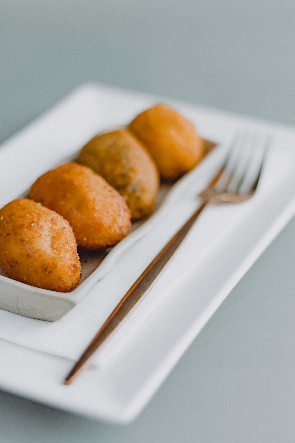 un plato blanco cubierto con tres alimentos fritos