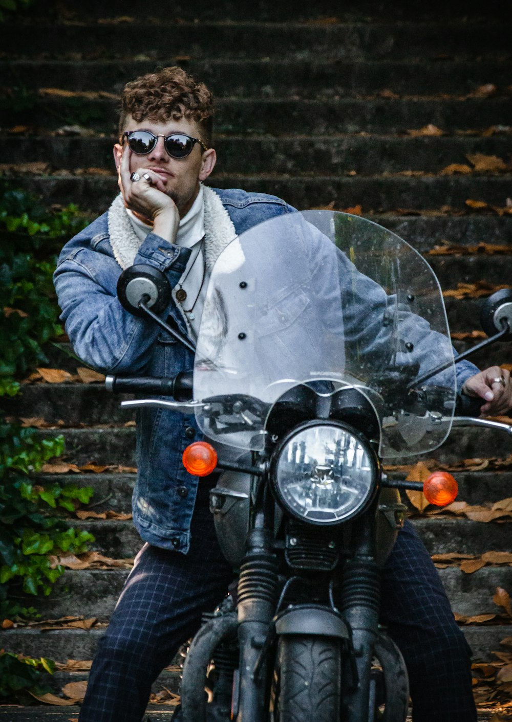 a man sitting on a motorcycle smoking a cigarette