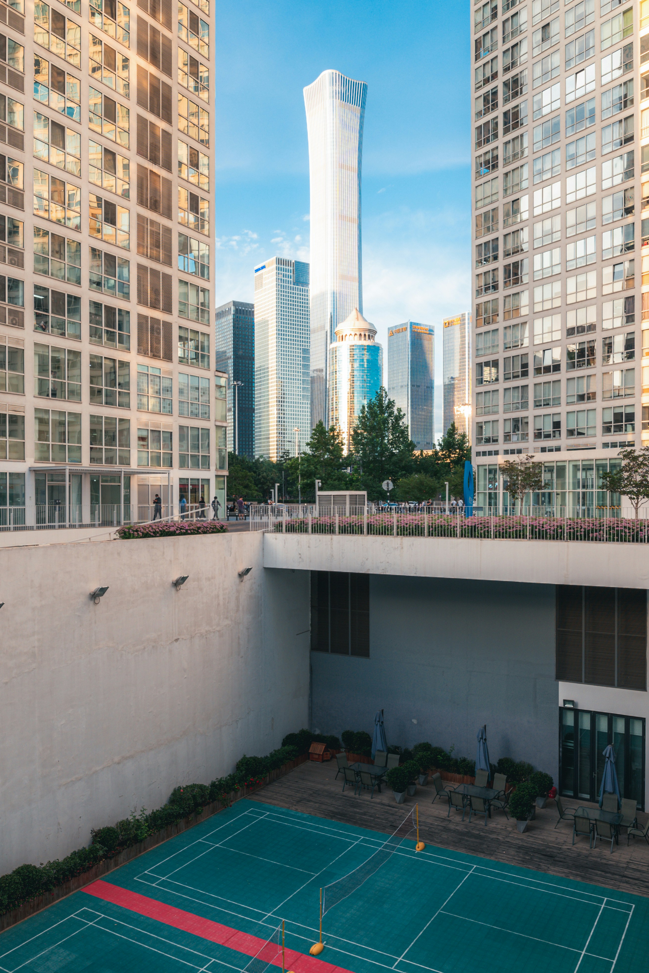 a tennis court surrounded by tall buildings in a city