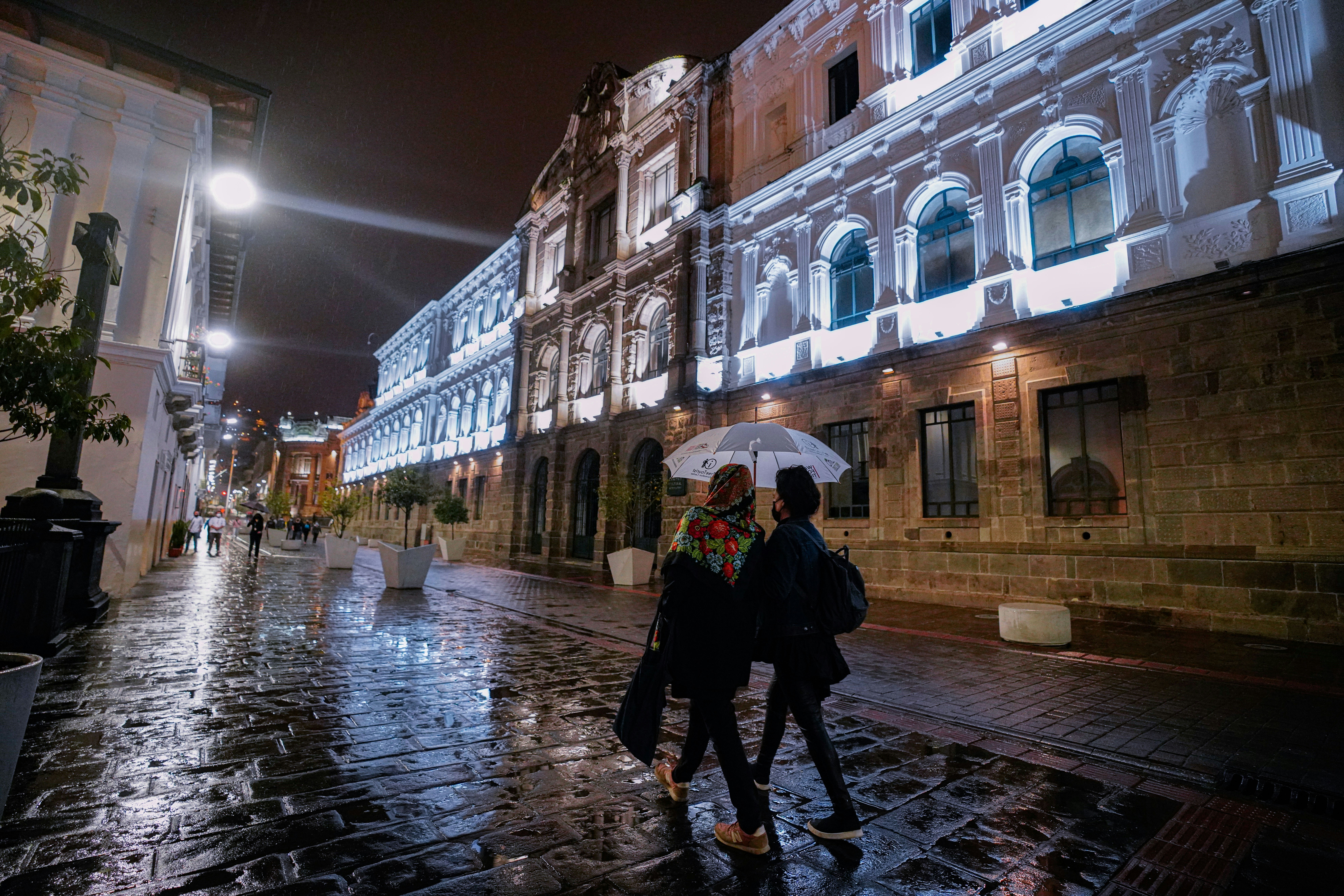 a couple of people walking down a street holding an umbrella